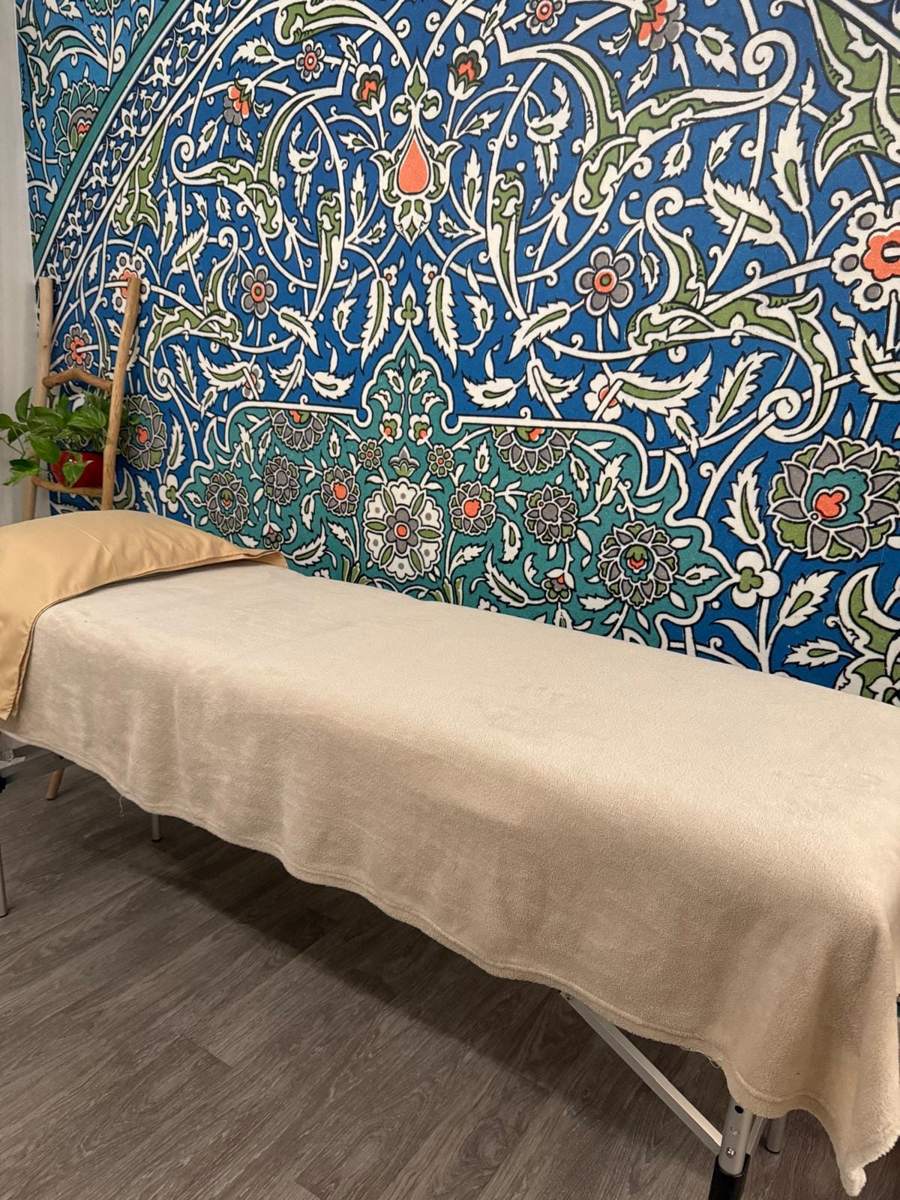 Le cabinet d'Amelle B à Épinay-sur-Seine, table de soin devant une fresque