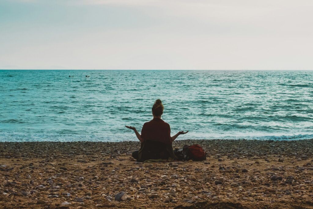 Soin énergétique et anxiété - femme en méditation yoga face à la mer, soulagement naturel des angoisses
