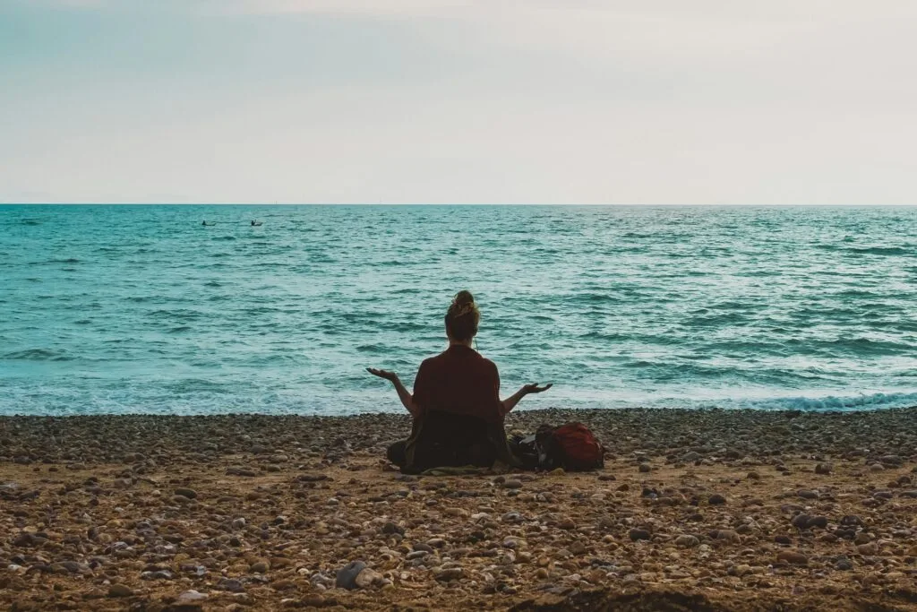 Soin énergétique et anxiété - femme en méditation yoga face à la mer, soulagement naturel des angoisses