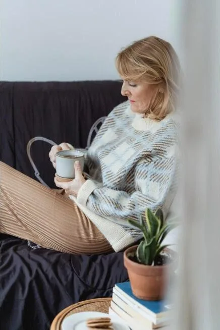 Femme d'âge mûr sereine savourant un thé chaud, illustrant l'apaisement pendant la ménopause