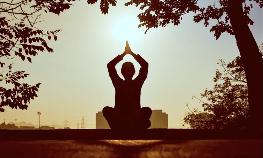 Silhouette en méditation face au lever du soleil, symbole d'énergie retrouvée face à la fatigue chronique