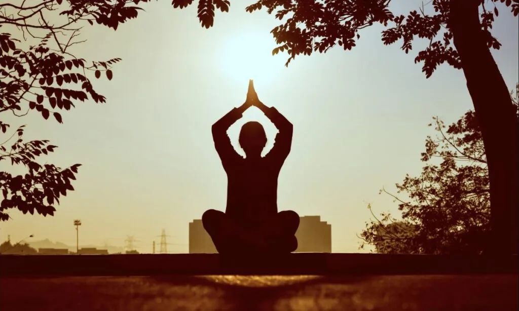 Silhouette en méditation face au lever du soleil, symbole d'énergie retrouvée face à la fatigue chronique